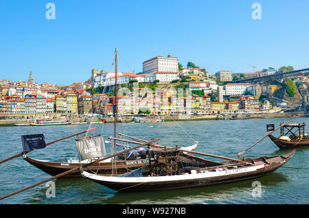 Porto, Portugal - 31. August 2018: traditionelle hölzerne Boote für Weinfass Transport auf dem Fluss Douro verwendet. Historische Altstadt im Hintergrund. Sommertag. Wunderschöne portugiesische Stadt. Stockfoto