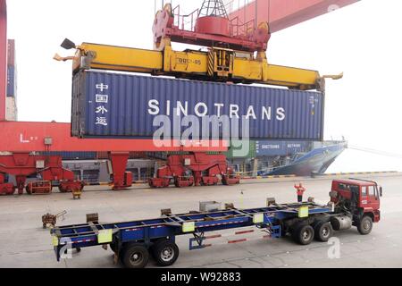 Ein Kran Fahrzeug entlädt einen Behälter mit Sinotrans im Ausland von einem Lkw im Hafen von Qingdao in Qingdao Stadt versendet werden, East China Shandong provin Stockfoto