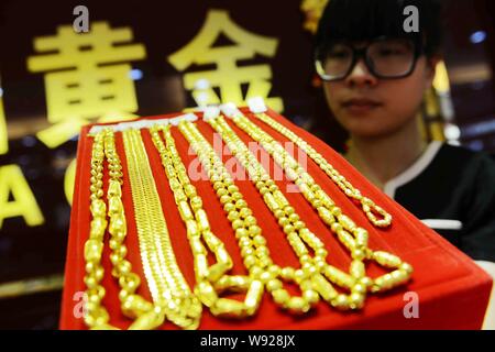 Eine chinesische Angestellte zeigt Gold Halsketten an einem gold Shop in Qingdao, China Provinz Shandong, 27. Juni 2013. Gold fiel unter $ 1.200 am Freitag (28 Ju Stockfoto