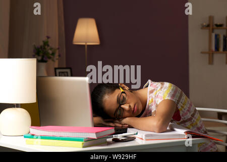 Teenager-Mädchen, die in einem Arbeitszimmer auf einem Schreibtisch nappen Stockfoto