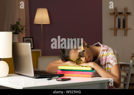 Teenager-Mädchen, die in einem Arbeitszimmer auf einem Schreibtisch nappen Stockfoto