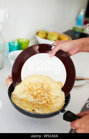 Nahaufnahme von einem kaukasischen Mann in der Küche vorbereiten eines typischen Tortilla de patatas, ein spanisches Omelette, mit Bratkartoffeln gemacht Stockfoto