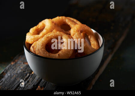 Nahaufnahme von einem weißen Keramik Schüssel mit calamares a la Romana, gebratene zerschlagene Tintenfischringe typisch für Spanien, auf einem dunklen rustikalen Holztisch Stockfoto