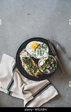 Gesundes Frühstück mit Avocado Toast, Spiegelei und Salat Stockfoto