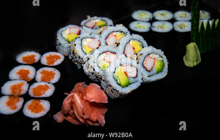 Eine Nahaufnahme von einer Auswahl an Hosomaki und California Sushi Rollen serviert mit Ingwer und Wasabi Stockfoto