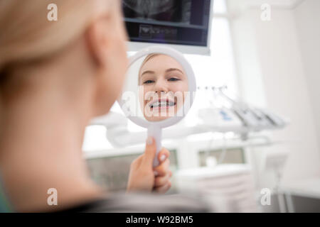Junge Frau lächelnd in den Spiegel. Stockfoto