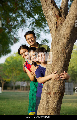 Familie guckt aus hinter Baum Stockfoto