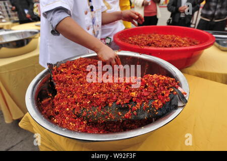 Eine chinesische Chef setzt Peperoni auf einem riesigen Fisch Kopf während der 23 chinesischen Koch Festival in Changsha, Provinz Hunan, China 19 Octobe gewürfelt Stockfoto