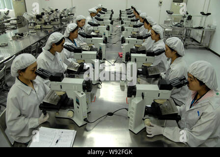 ------ Junge weibliche Chinesische neu selbständigen Betrieb Mikroskope während einer Schulung in einer Anlage in Dongguan City, South China Guangdong Stockfoto