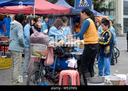------ Junge Chinesische Wanderarbeiter kaufen Frühstück essen an einem Stand auf der Straße in Dongguan City, South China Guangdong Provinz, vom 8. Januar 2010. Stockfoto