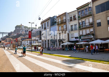 Porto, Portugal - 31. August 2018: die Menschen zu Fuß über die Promenade am Fluss Douro an einem sonnigen Tag. Der Damm ist voll von Restaurants, Bars und Weinkeller für die Reifung der berühmte Portwein verwendet. Stockfoto