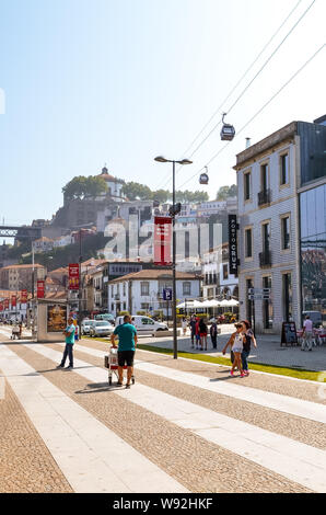 Porto, Portugal - 31. August 2018: Touristen zu Fuß über die Promenade am Fluss Douro an einem sonnigen Tag. Der Damm ist voll von Restaurants, Bars und Weinkeller für die Reifung der berühmte Portwein verwendet. Stockfoto