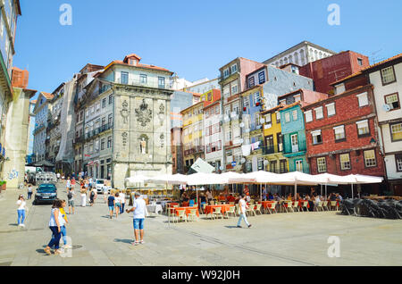 Porto, Portugal - 31. August 2018: Menschen auf der Promenade am Fluss Douro an einem sonnigen Tag. Der Damm ist voll von Restaurants, Bars und Weinkeller für die Reifung der berühmte Portwein verwendet. Bunte Fassaden. Stockfoto