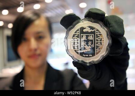 ---- Eine chinesische Angestellte zeigt eine silberne mooncake an einem gold Shop in Zhoukou City, Central China Provinz Henan, 29. August 2013. China hat offi verboten Stockfoto