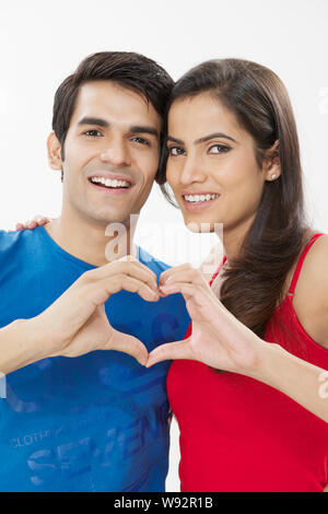 Junges Paar macht Herzform mit Händen und lächelnd Stockfoto