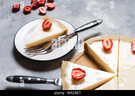 Hausgemachter Käsekuchen mit frischen Erdbeeren in Scheiben geschnitten auf konkreten Hintergrund Stockfoto