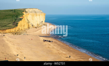 Bridport, Dorset, Großbritannien - 28 März 2019: Leute Spaziergang entlang dem Strand von Burton Bradstock auf in Dorset Jurassic Coast. Stockfoto