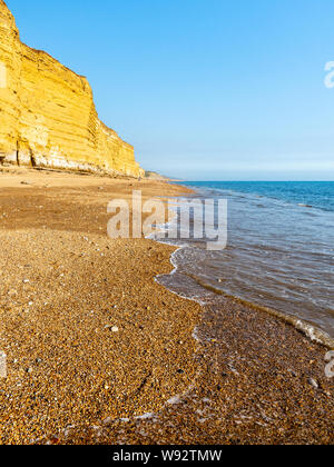 Sonne scheint auf den Schindel der Hive Strand, Teil der Chesil Beach, unter der Sandsteinfelsen von Burton Bradstock auf in Dorset Jurassic Coast. Stockfoto