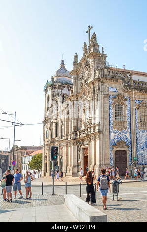 Porto, Portugal - 31. August 2018: Die Menschen auf der Straße von den berühmten Kirchen Igreja do Carmo und angrenzenden Igreja dos Carmelitas. Traditionelle portugiesische Kacheln azulejos auf Kirche Fassade. Straße mit Menschen. Stockfoto