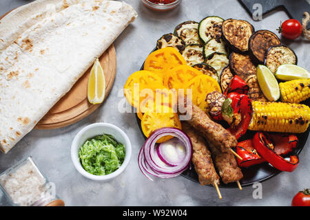 Verschiedene köstliche gegrillte Gemüse und Fleisch auf einen konkreten Hintergrund. Sommer essen Grill. Stockfoto