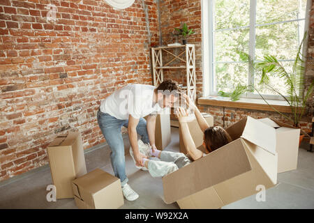 Junges Paar zog in ein neues Haus oder Wohnung. Spaß mit Kartons, Entspannung nach Reinigung und Auspacken am Tag verschoben. Glücklich aus. Familie, Verschieben, Beziehungen, erste Home Konzept. Stockfoto