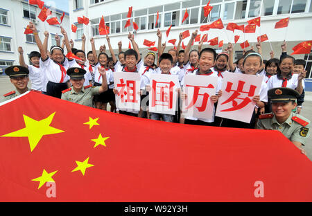 Junge chinesische Studenten wave kleine chinesische nationale Flaggen als paramilitärischen Polizisten Anzeige einer großen nationalen Tag der kommenden Feiertage zu feiern ein Stockfoto