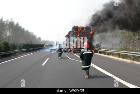 Chinesische Feuerwehrmänner Schlauch Wasser in das Feuer auf ein Fahrzeug mit Baumwolle auf dem Xuchang-Pingdingshan Nanyang Expressway in der Nähe von xuchang Stadt geladen zu löschen, Stockfoto