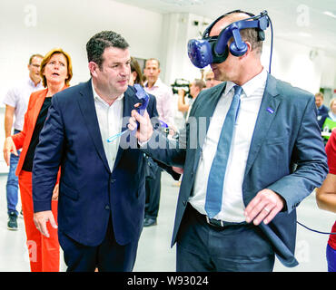 Ludwigshafen, Deutschland. 12 Aug, 2019. Martin Brudermüller (r), Vorsitzender des Vorstands des Chemiekonzerns BASF, steht neben Hubertus Heil (SPD), Bundesminister für Arbeit und Soziales, und versucht die virtual reality Brillen auf dem Gelände des Chemiekonzerns BASF. Hinter Ihnen ist Malu Dreyer (l, SPD), Ministerpräsident von Rheinland-Pfalz. Der Sekretär der Arbeit ist auf einer Sommerreise. Foto: Uwe Anspach/dpa/Alamy leben Nachrichten Stockfoto