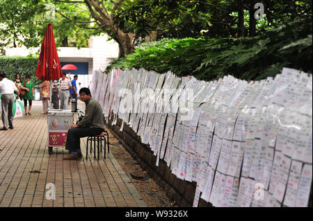 Leute schauen auf Stücke von Kontaktinformationen auf dem Heiratsmarkt in Shanghais Völker Platz in Shanghai, China, 30. Juni 2013. Die Ehe Marke Stockfoto