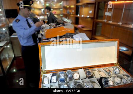 Chinesische Polizeibeamte fake Luxusmarke Uhren und andere Waren, die in einem Shop in Peking, China, Konfiszieren, 13. Mai 2013. Beijing Polizei und l Stockfoto