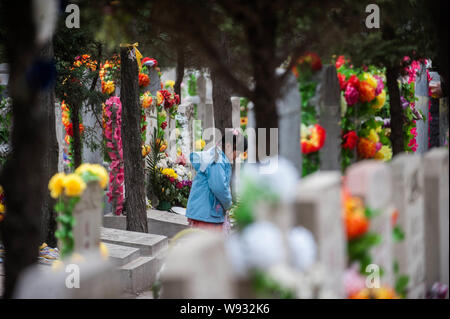 Ein junges Mädchen steht vor dem Grab eines verstorbenen Verwandten während Qingming Festival, oder Grab fegen Tag, am Babaoshan Friedhof in Peking, Stockfoto