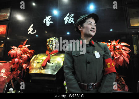 Eine Kellnerin in roten Garde Uniform begrüßt Kunden vor einer Büste von Mao Zedong am Maos Restaurant in Stadt Bozhou, East China Provinz Anhui, Stockfoto