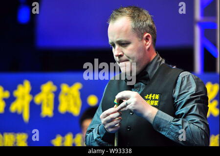 John Higgins von England Kreiden seine Cue als hält er einen Schuß gegen Ding Junhui in China während einer Viertelfinalegleichen der 2013 Haikou World Open i Stockfoto