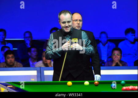 John Higgins von England Kreiden seine Cue als hält er einen Schuß gegen Ding Junhui in China während einer Viertelfinalegleichen der 2013 Haikou World Open i Stockfoto