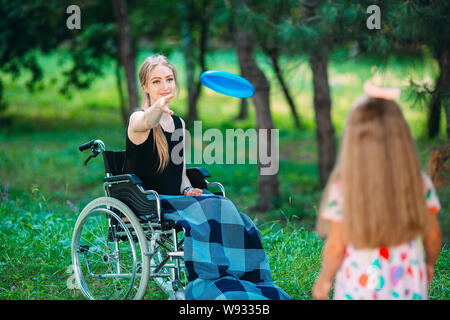 Eine junge behinderte Mädchen spielt Frisbee mit ihrer jüngeren Schwester. Interaktion von einer gesunden Person mit einer behinderten Person Stockfoto