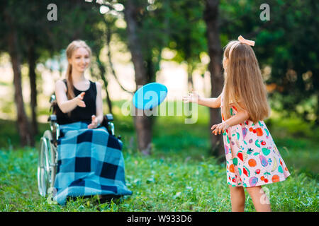 Eine junge behinderte Mädchen spielt Frisbee mit ihrer jüngeren Schwester. Interaktion von einer gesunden Person mit einer behinderten Person Stockfoto