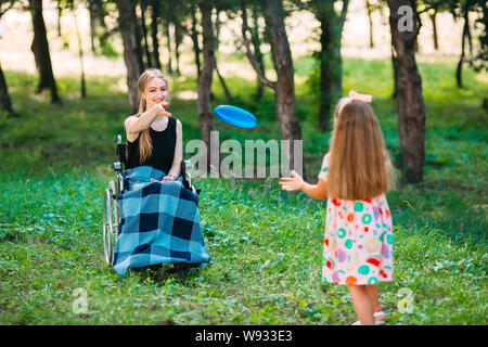 Eine junge behinderte Mädchen spielt Frisbee mit ihrer jüngeren Schwester. Interaktion von einer gesunden Person mit einer behinderten Person Stockfoto