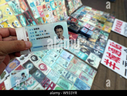 Ein Mann zeigt eine gefälschte Chinesischen ID-Karte von Hongkong Sänger und Schauspieler Nicholas Tse zum Verkauf an einen Stand auf einer Straße in Guangzhou City, South China Guangdon Stockfoto