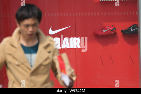 ---- Ein Fußgänger geht hinter einem Sportswear Store von Nike in Qingdao Stadt, East China Provinz Shandong, 16. März 2013. Es wurde im letzten Juni, dass Nike Stockfoto