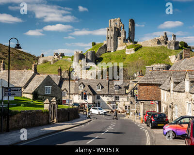 Corfe Castle, England, UK - 27. März 2019: Sonne scheint auf den Ruinen der mittelalterlichen Burg über Corfe Castle Dorf in Dorset. Stockfoto