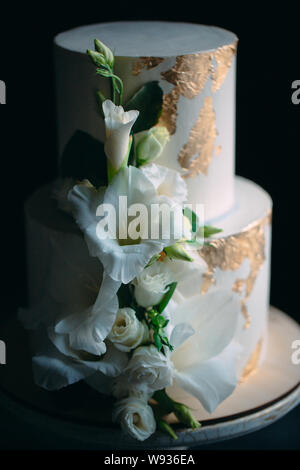 Zwei-klassen-Kuchen mit Blumen auf einem Stand aus Holz auf einem schwarzen Hintergrund. Stockfoto