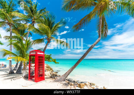 Iconic red britische Telefonzelle vor der klaren Karibischen Meer, Siboney Beach, Dickenson Bay, Antigua Stockfoto