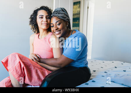 Portrait von sicher glücklich Lesben auf dem Bett zu Hause sitzen Stockfoto