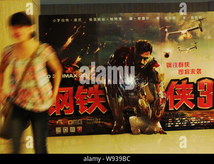 Eine Frau geht Vergangenheit ein Poster zum Film Iron Man 3 an einem Kino in Kunshan City, Central China Provinz Hubei, 1. Mai 2013. Iron Man 3 hat bekräftigt Ho Stockfoto