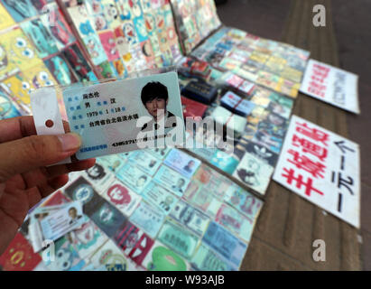 Ein Mann zeigt eine gefälschte Chinesischen ID-Karte der taiwanesischen Sänger und Schauspieler Jay Chou für Verkauf an einen Stand auf einer Straße in Guangzhou City, South China Guangdong pr Stockfoto