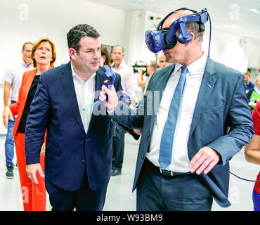 Ludwigshafen, Deutschland. 12 Aug, 2019. Martin Brudermüller (r), Vorsitzender des Vorstands des Chemiekonzerns BASF, steht neben Hubertus Heil (SPD), Bundesminister für Arbeit und Soziales, und versucht die virtual reality Brillen auf dem Gelände des Chemiekonzerns BASF. Hinter Ihnen ist Malu Dreyer (l, SPD), Ministerpräsident von Rheinland-Pfalz. Der Sekretär der Arbeit ist auf einer Sommerreise. Foto: Uwe Anspach/dpa/Alamy leben Nachrichten Stockfoto