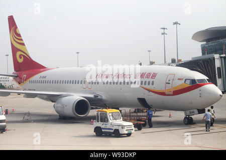 ---- Chinesischen Boden Crew Mitglieder arbeiten neben einer Boeing 737-800 Düsenflugzeug von Hainan Airlines am Changsha Huanghua Internationalen Flughafen in Chang Stockfoto