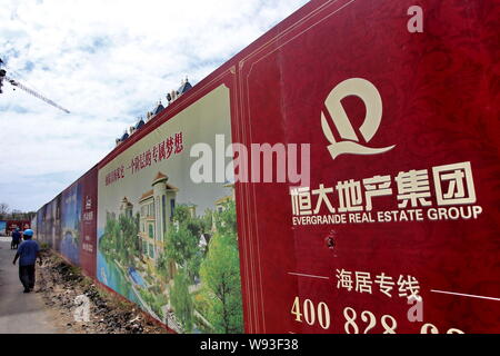 ---- Ein chinesischer Wanderarbeiter an eine Werbung für Evergrande Real Estate Group auf einer Baustelle in Xi'an, China Jiangsu pr Stockfoto