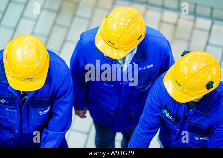 Ludwigshafen, Deutschland. 12 Aug, 2019. Auszubildende, die in blauen Anzüge und gelb Bauarbeiter Helm gekleidet, arbeiten in einer Produktionshalle des Chemiekonzerns BASF. Minister für Beschäftigung Heil ist auf einer Sommerreise. Foto: Uwe Anspach/dpa/Alamy leben Nachrichten Stockfoto
