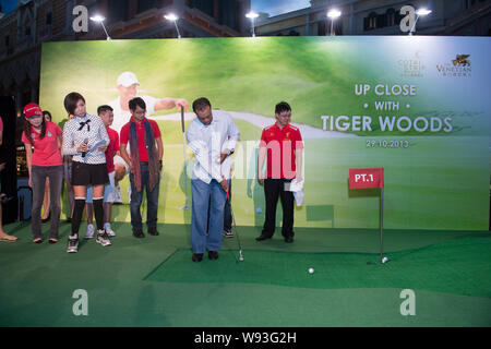 Golfspieler Tiger Woods der Vereinigten Staaten, vorne rechts, T-Stücke mit einer Hand während einer Fan Meeting Veranstaltung in Macau, China, 29. Oktober 2013. Stockfoto